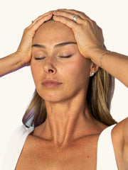 Ryan demonstrating The Unfurrowing, hands resting at her temples